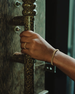 Imara Bangle by Umutoni. A timeless gold bangle inspired by strength and simplicity, handcrafted in Kenya. Available in classic and slim unisex styles.