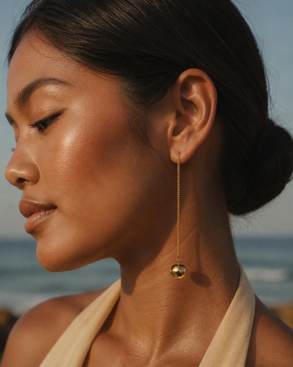 Model wearing Umutoni Anga gold earrings with refined summer occasion styling.