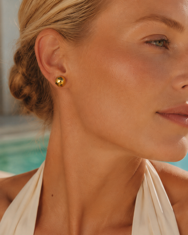 Model wearing Umutoni Nalla gold stud earrings, handmade in Kenya.